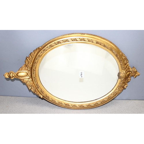 498C - An antique gilt framed oval mirror with decorative frame, approx 78cm x 47cm