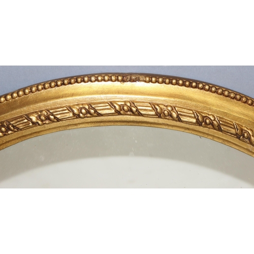 498C - An antique gilt framed oval mirror with decorative frame, approx 78cm x 47cm