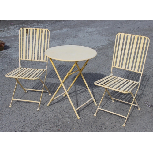 317 - A small faded yellow painted metal bistro set with 2 folding chairs and a table, approx 62cm wide x ... 