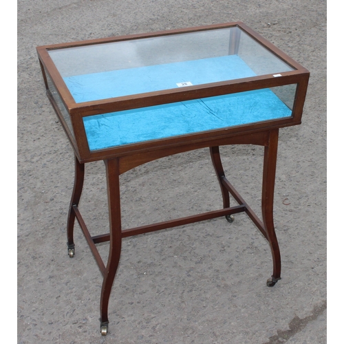 28 - A vintage glazed mahogany bijouterie table with thin legs and castors, approx 66cm wide x 47cm deep ... 