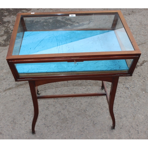 28 - A vintage glazed mahogany bijouterie table with thin legs and castors, approx 66cm wide x 47cm deep ... 