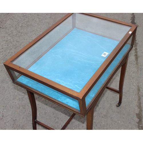 28 - A vintage glazed mahogany bijouterie table with thin legs and castors, approx 66cm wide x 47cm deep ... 