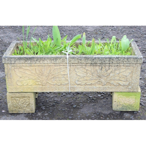 306 - A reconstituted stone garden trough planter with feet and moulded oak leaf decoration, with plants, ... 