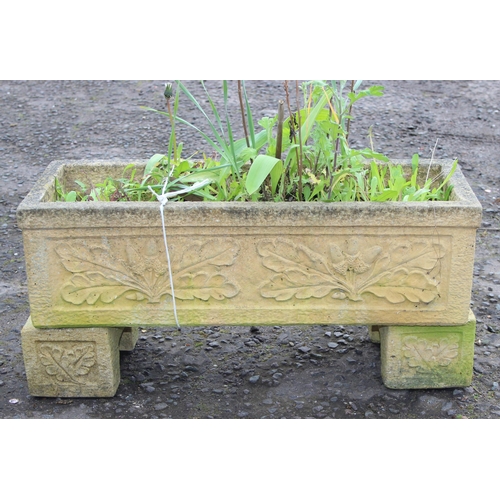 307 - A reconstituted stone garden trough planter with feet and moulded oak leaf decoration, with plants, ... 