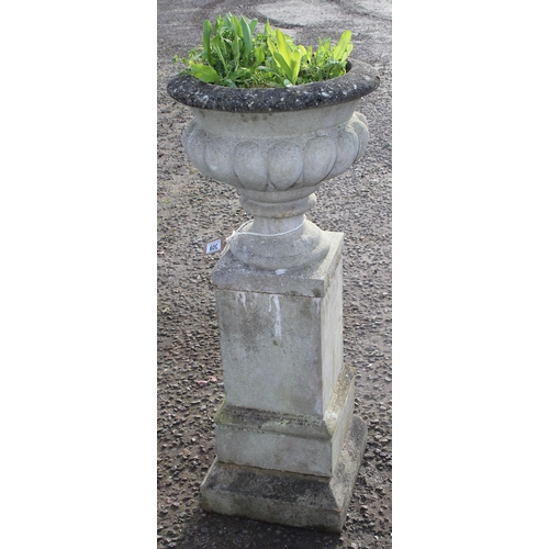 302 - A large weathered reconstituted stone urn on plinth, approx 42cm wide x 42cm deep x 110cm tall