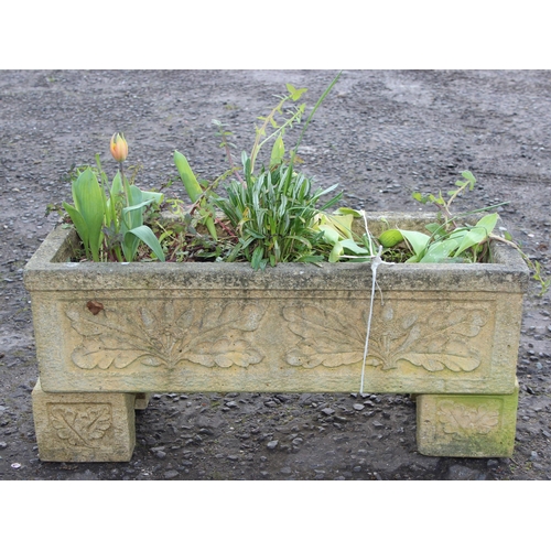 308 - A reconstituted stone garden trough planter with feet and moulded oak leaf decoration, with plants, ... 