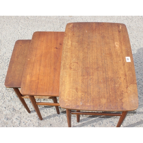 69 - A retro teak nest of 3 tables, the smallest with rattan magazine rack, strongly in the manner of Dan... 