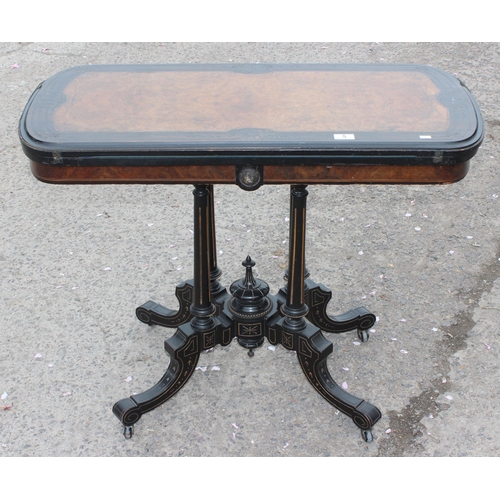 5 - A Victorian burr walnut and ebonised card or games table standing on pillar supports with blue baize... 