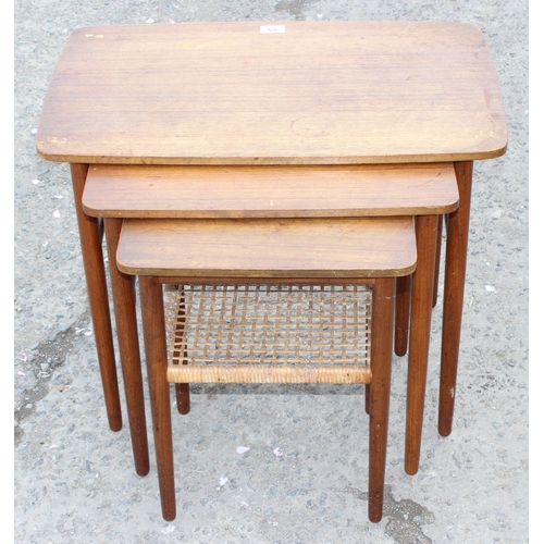 69 - A retro teak nest of 3 tables, the smallest with rattan magazine rack, strongly in the manner of Dan... 