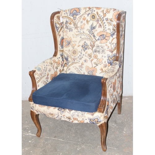 96 - An antique wingback armchair with wooden frame and William Morris style upholstery