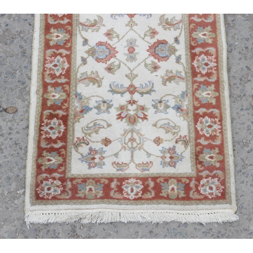 214 - A vintage hand made cream ground runner rug with decorative red border, approx 180cm wide x 62cm dee... 