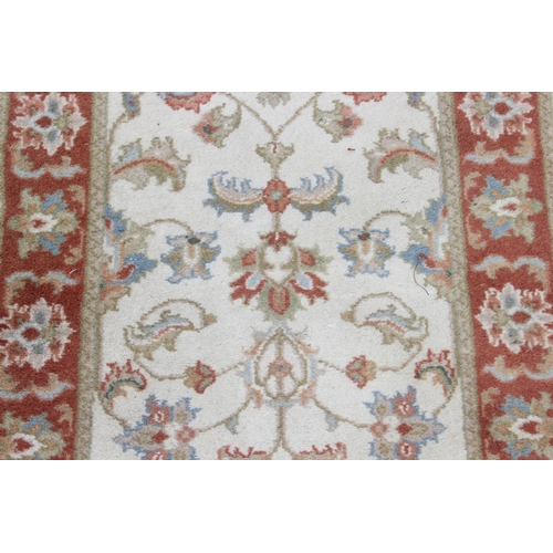 214 - A vintage hand made cream ground runner rug with decorative red border, approx 180cm wide x 62cm dee... 