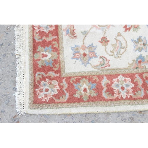 214 - A vintage hand made cream ground runner rug with decorative red border, approx 180cm wide x 62cm dee... 