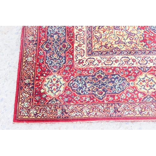 219 - A large Persian style highly decorative red ground rug, approx 320cm x 275cm