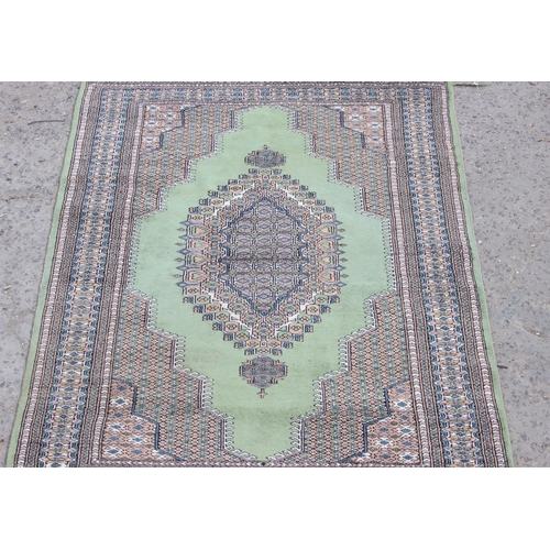 221 - A large decorative green and patterned Persian style rug, approx 210cm x 123cm