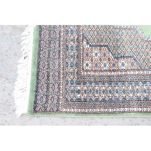 221 - A large decorative green and patterned Persian style rug, approx 210cm x 123cm