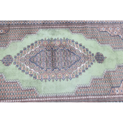 221 - A large decorative green and patterned Persian style rug, approx 210cm x 123cm