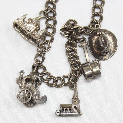 1160K - A vintage silver charm bracelet with charms to inc St Paul's Cathedral, Cowboy Hat, Garden Roller et... 