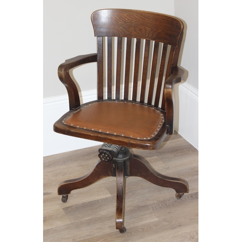 93 - An early 20th century oak captain's chair or desk chair with slat back and leather seat, approx 90cm... 