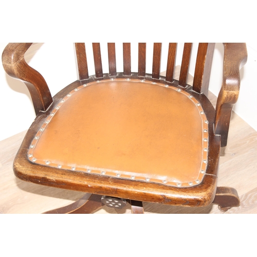 93 - An early 20th century oak captain's chair or desk chair with slat back and leather seat, approx 90cm... 