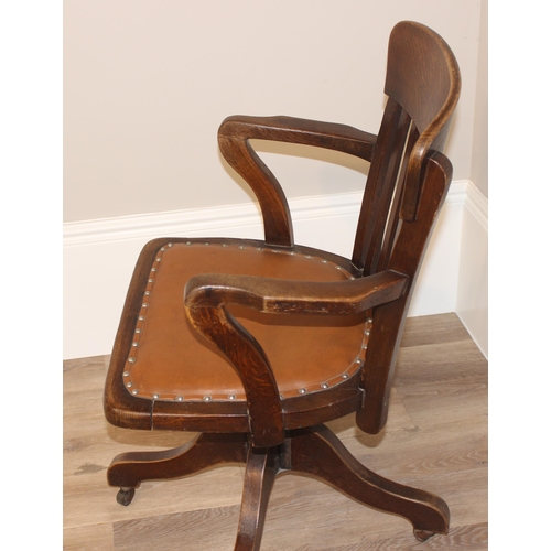 93 - An early 20th century oak captain's chair or desk chair with slat back and leather seat, approx 90cm... 