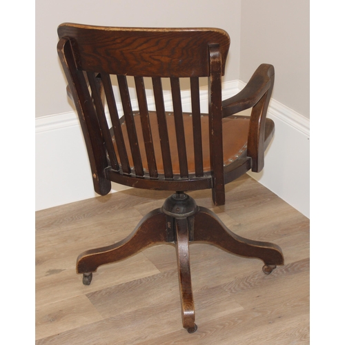 93 - An early 20th century oak captain's chair or desk chair with slat back and leather seat, approx 90cm... 