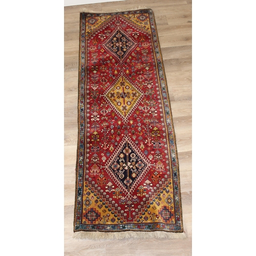 210 - A highly decorative hand made runner rug of red ground, likely Turkish, approx 210cm x 76cm