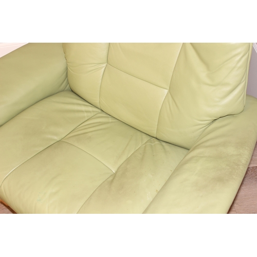 39 - A light green leather Ekornes Stressless armchair and a similar footstool, approx 104cm wide x 81cm ... 