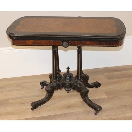 92 - A Victorian burr walnut and ebonised card or games table standing on pillar supports with blue baize... 