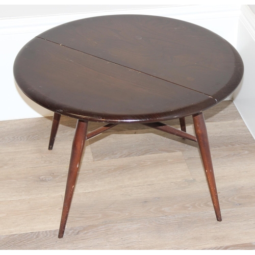 131 - A vintage Ercol drop leaf round coffee table with original blue and gold label, approx 61cm wide x 6... 