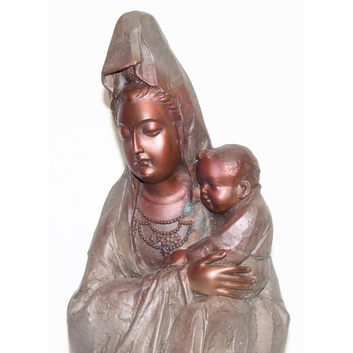 1556 - A large bronzed-metal figure of Guanyin, the Goddess of Mercy with child, indistinctly signed to rev... 