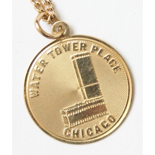 1101 - An American 14ct gold necklace with 14ct gold pendant depicting Water Tower Place Chicago, marked an... 