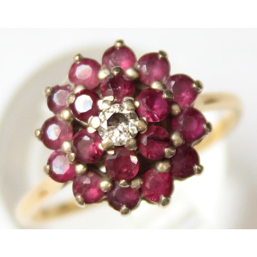 1104 - An 18ct gold diamond and ruby floral cluster ring, a small central diamond surrounded by 18 small ru... 