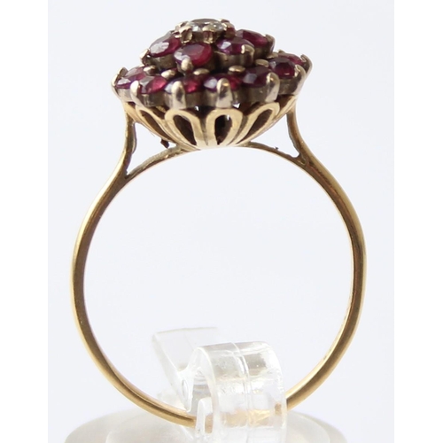 1104 - An 18ct gold diamond and ruby floral cluster ring, a small central diamond surrounded by 18 small ru... 