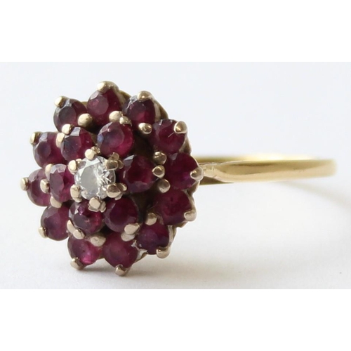 1104 - An 18ct gold diamond and ruby floral cluster ring, a small central diamond surrounded by 18 small ru... 