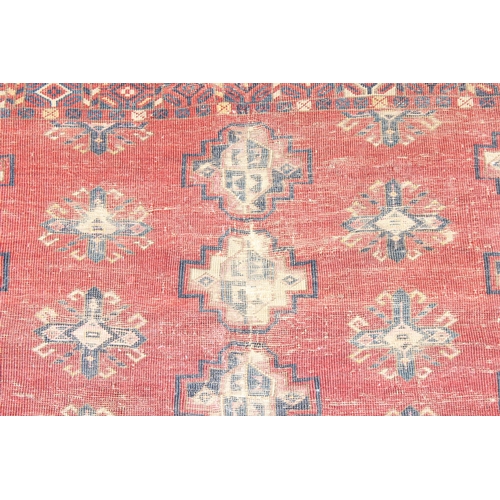 213 - A vintage Turkoman style rug of red ground with various gul decoration, approx 130cm x 88cm