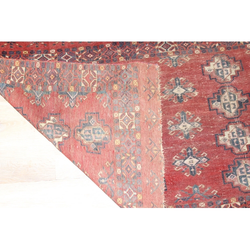 213 - A vintage Turkoman style rug of red ground with various gul decoration, approx 130cm x 88cm