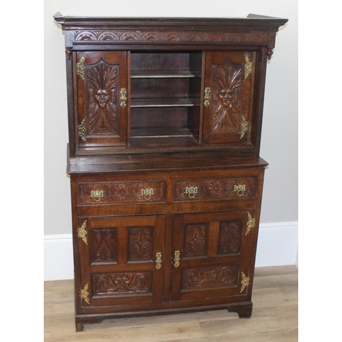 45 - A vintage oak court cupboard with profusely carved detail and brass fittings, approx 111cm wide x 57... 