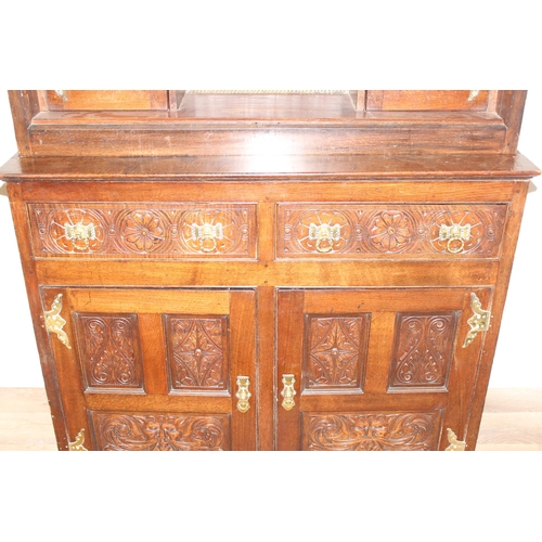 45 - A vintage oak court cupboard with profusely carved detail and brass fittings, approx 111cm wide x 57... 