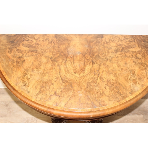 81 - A Victorian burr walnut card table with swivel, fold over top, and decorative carved base with 5 pil... 