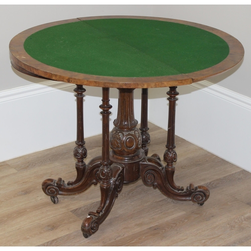 81 - A Victorian burr walnut card table with swivel, fold over top, and decorative carved base with 5 pil... 