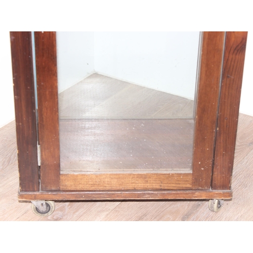 99 - Vintage stained pine and glass sided display cabinet with glass shelves and front castors, approx 44... 