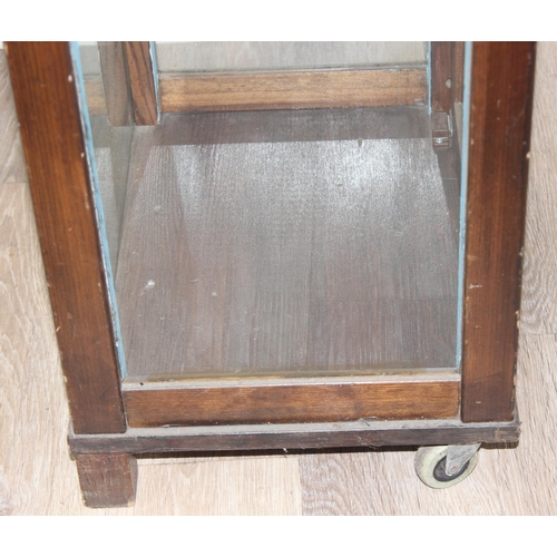 99 - Vintage stained pine and glass sided display cabinet with glass shelves and front castors, approx 44... 