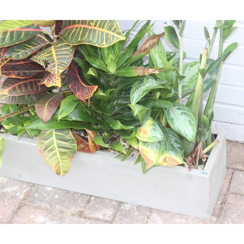 379 - A grey fiberglass garden trough planter complete with soil, stones and plants, approx 72cm wide x 20... 