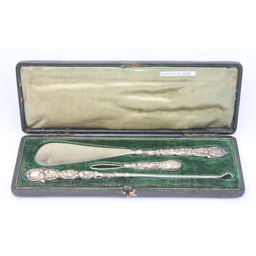 1010 - An antique boxed silver handled shoe horn and button hook set, indistinctly marked but in leather ca... 