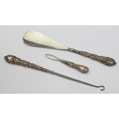 1010 - An antique boxed silver handled shoe horn and button hook set, indistinctly marked but in leather ca... 