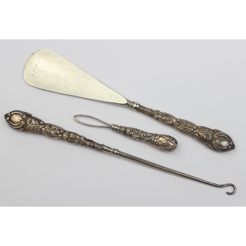 1010 - An antique boxed silver handled shoe horn and button hook set, indistinctly marked but in leather ca... 