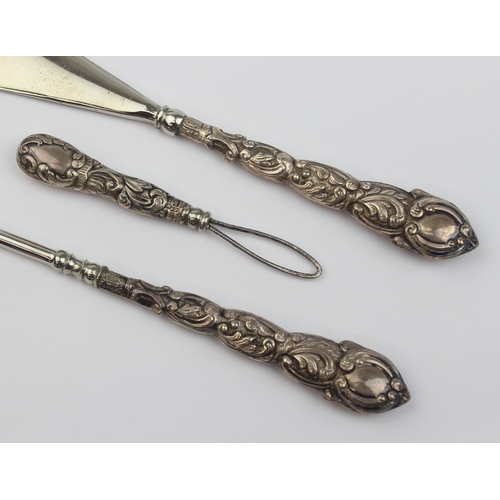 1010 - An antique boxed silver handled shoe horn and button hook set, indistinctly marked but in leather ca... 