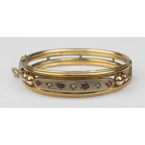 1100 - A Victorian 9ct gold cuff bangle set with rubies and diamonds, 4 rubies and 3 diamonds in star cut s... 