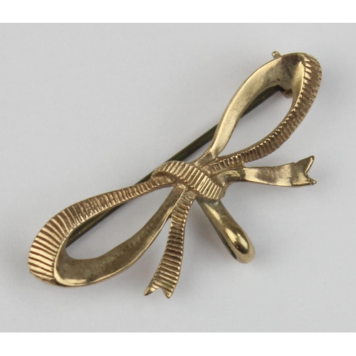 1108 - A 9ct gold brooch formed as a bow, marked and XRF confirmed, with base metal pin, approx 38mm wide, ... 